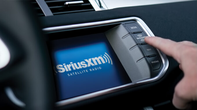 A man's hand pushing a button on a SiriusXM Satellite Radio